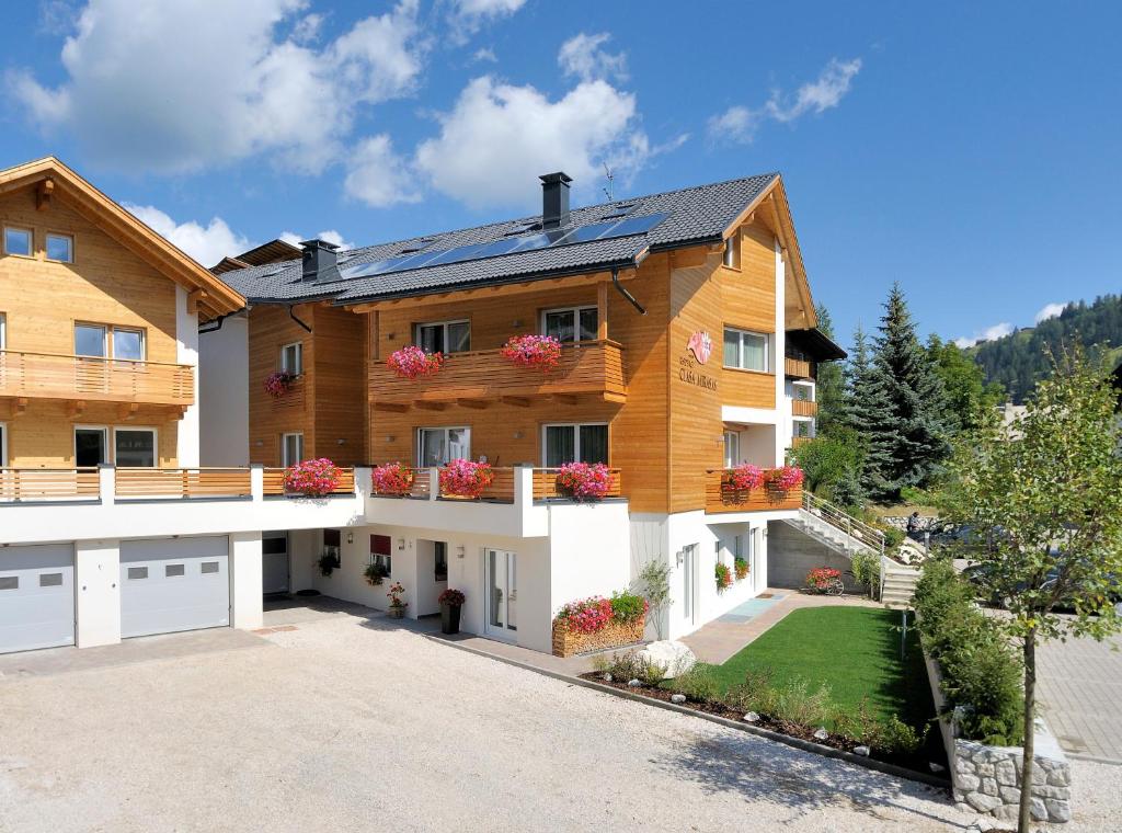 une grande maison en bois avec des fleurs sur les balcons dans l'établissement Residence Ciasa Mirasas, à Badia