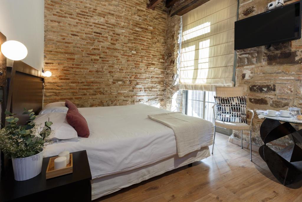 1 dormitorio con cama y pared de ladrillo en AinB Picasso-Corders Apartments, en Barcelona