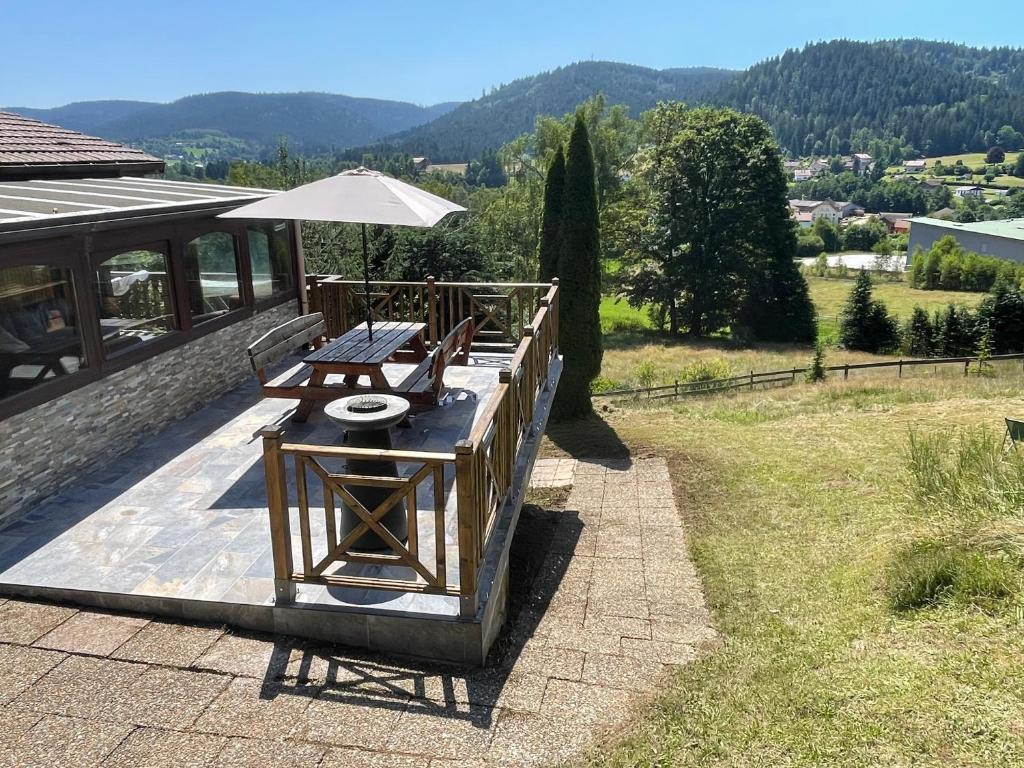 - une table de pique-nique avec un parasol sur la terrasse dans l'établissement Chalet les brimbelles, à Le Tholy