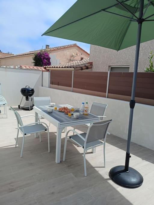 - une table et des chaises avec un parasol vert sur la terrasse dans l'établissement Villa année 2024 Bord de mer 6 pers, à Sainte-Marie-Plage