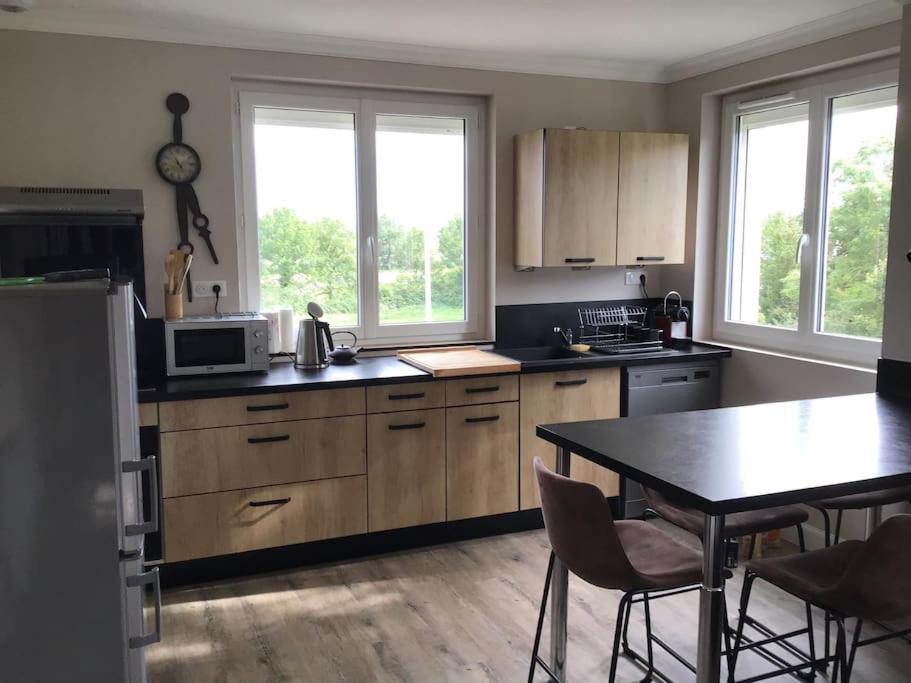 une cuisine avec des armoires en bois et une table avec des chaises dans l'établissement Appartement T3 labellisé 3 étoiles, à Aurillac