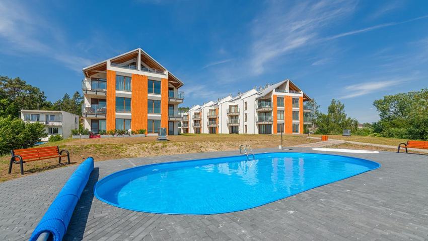 a swimming pool in front of a building at Apartament Diuna in Krynica Morska