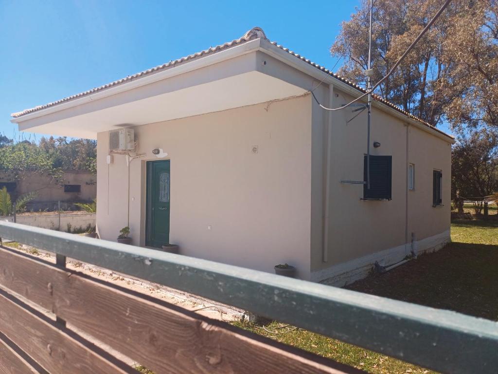 a small white building with a green door on a fence at Sunday Villa in Agios Georgios