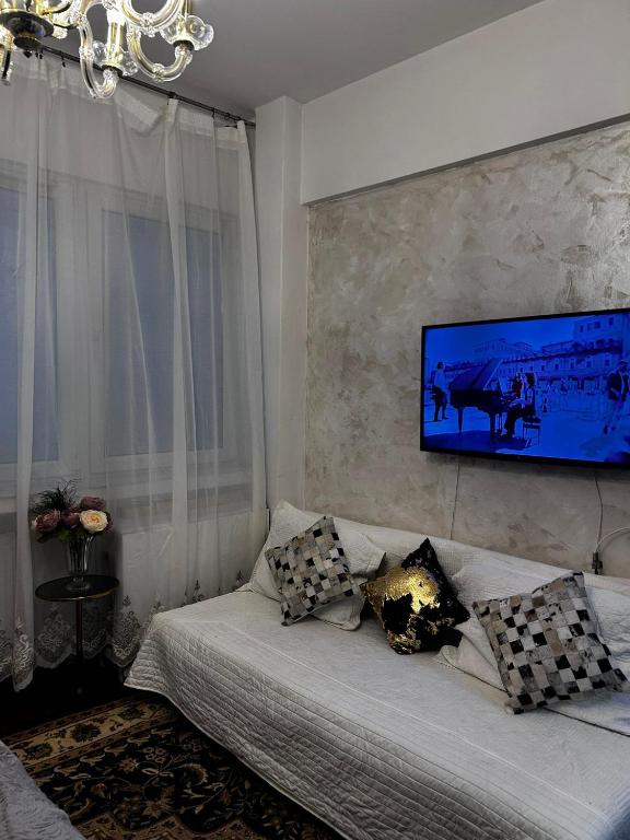 a living room with a couch with a tv on the wall at Mini scala in Bucharest