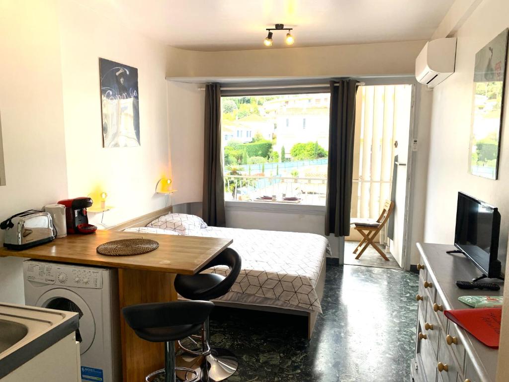Cette petite chambre comprend un lit, une table et une cuisine. dans l'établissement Cannes center terrace AC Wifi 200 m from sea behind Martinez, à Cannes