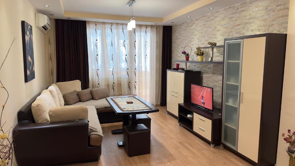 a living room with a couch and a tv at Уютен апартамент в централната част на Стара Загора in Stara Zagora