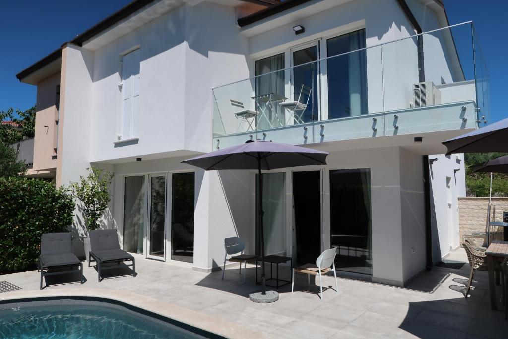 a house with a pool and chairs and an umbrella at Art Villa Malija in Portorož