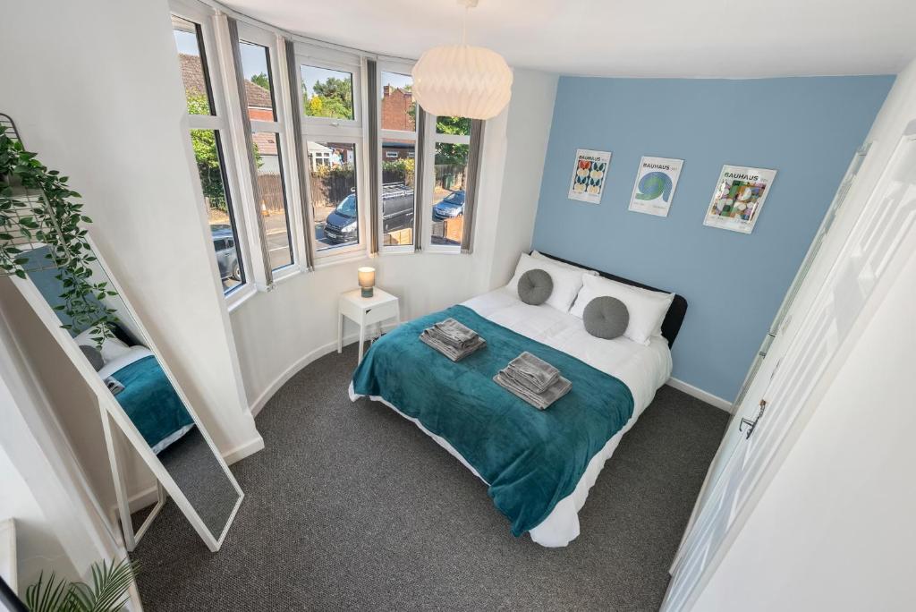a small bedroom with a bed and windows at 4BR 3 bath Spacious apartment, Sleeps upto 8 free parking in Allesley