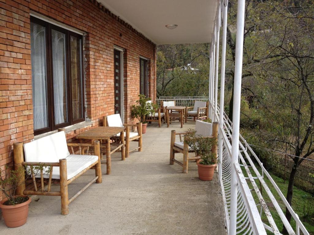 - un balcon avec des chaises et des tables en bois dans un bâtiment en briques dans l'établissement Villa Gelati, à Koutaïssi