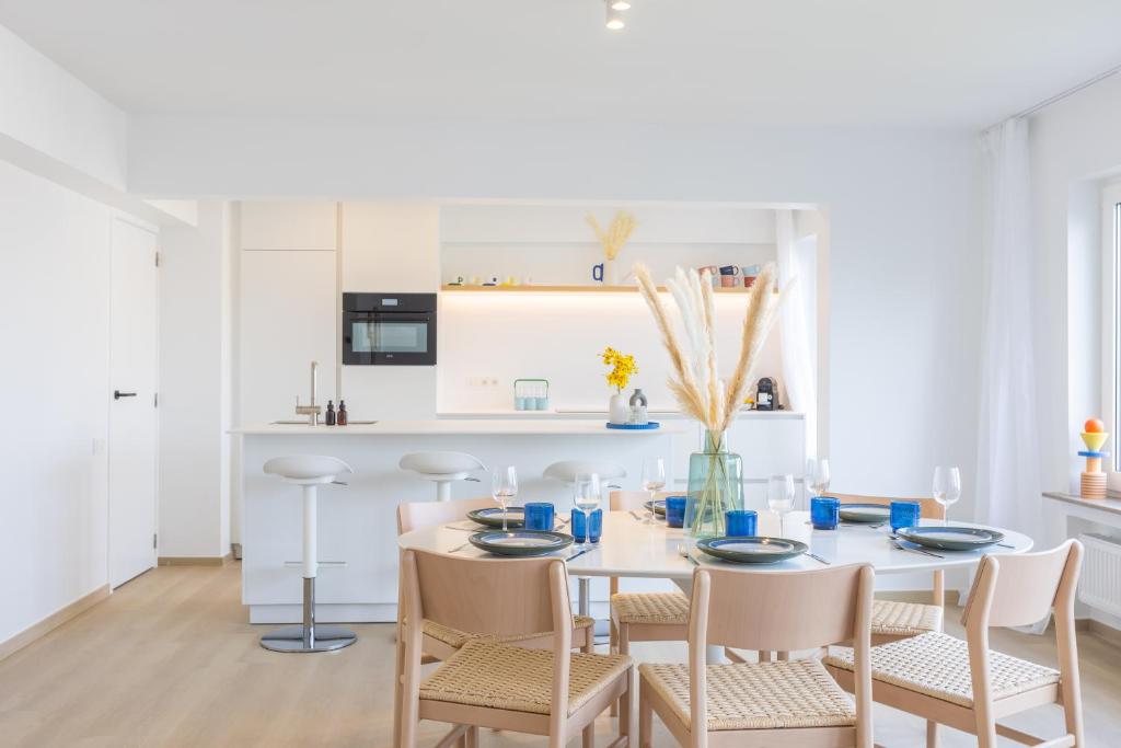 een witte eetkamer met een tafel en stoelen bij Maison Anna by Exclusive-Stays in Oostende