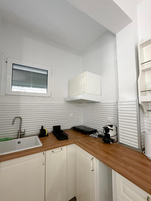 a kitchen with white cabinets and a sink and a window at Petra Mare Apartments in Alyki