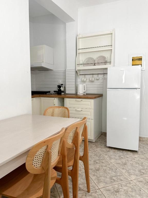 a kitchen with a white refrigerator and a table and chairs at Petra Mare Apartments in Alyki