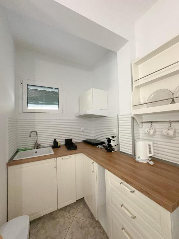a kitchen with white cabinets and a wooden counter top at Petra Mare Apartments in Alyki