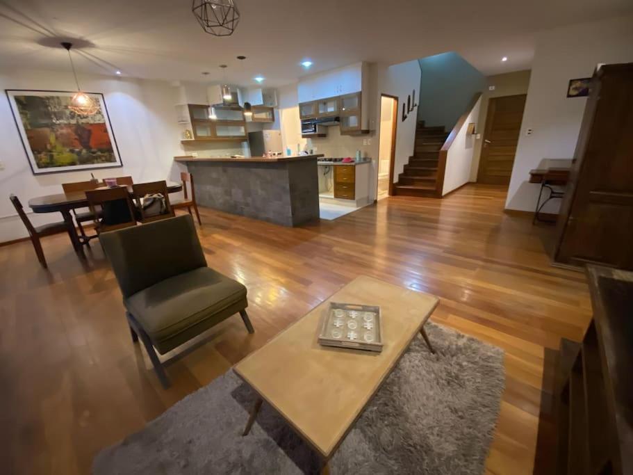 a living room with a coffee table and a kitchen at Departamento de 2 pisos en zona norte Cochabamba in Cochabamba