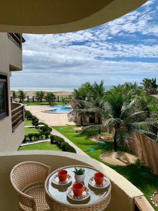 a balcony with a table and chairs and a pool at Flat Marezzi - Pé na areia - Taíba CE in São Gonçalo do Amarante