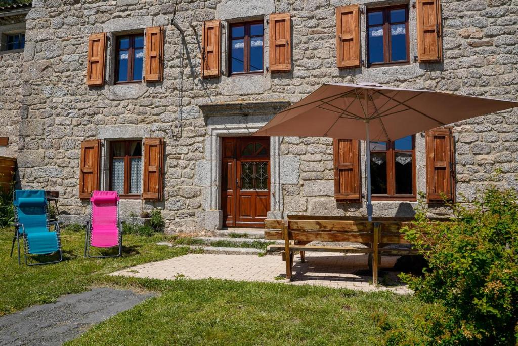 a bench and an umbrella in front of a building at la margeride in Le Malzieu Forain