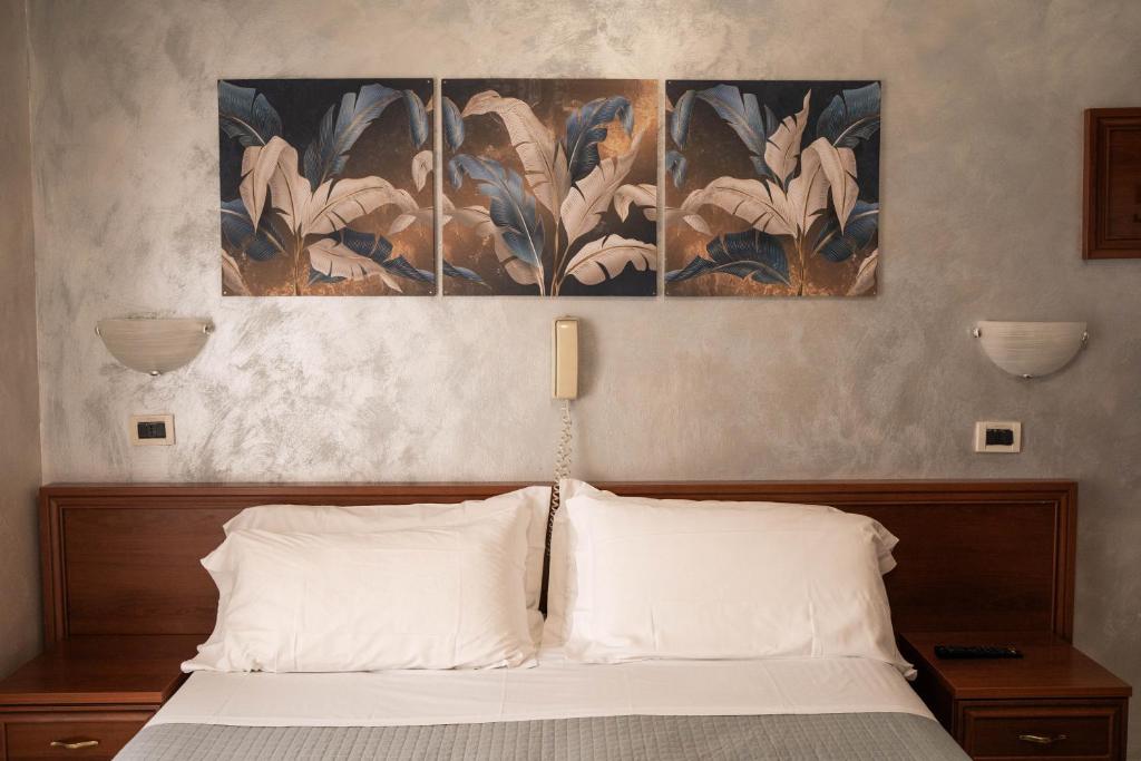 a bedroom with a bed with two paintings on the wall at Hotel Marconi in Fiuggi