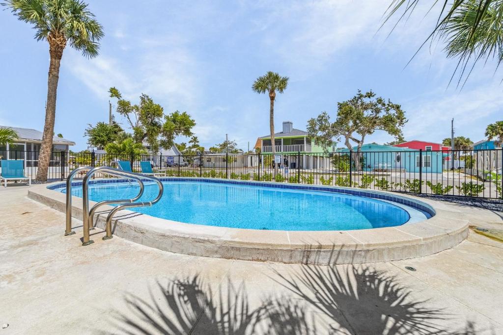 a swimming pool at a resort with palm trees at Dune Our Thing - Building A - 171 Washington condo in Fort Myers Beach