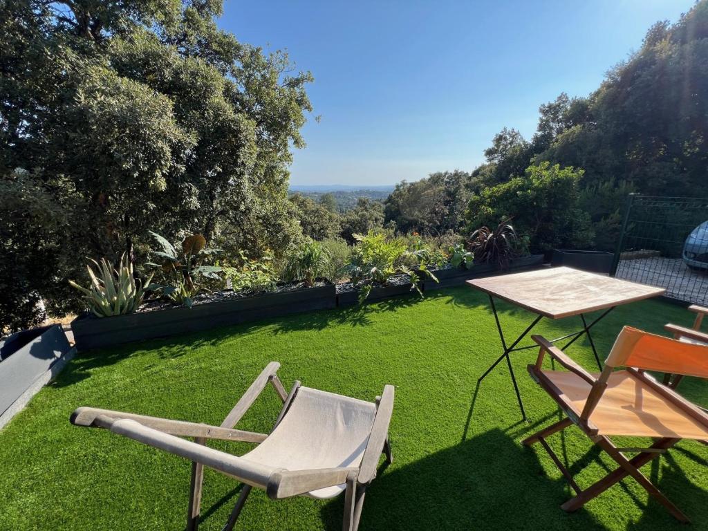 a lawn with two chairs and a table on it at Appartement Valcros - Jardin Vue Mer in La Londe-les-Maures