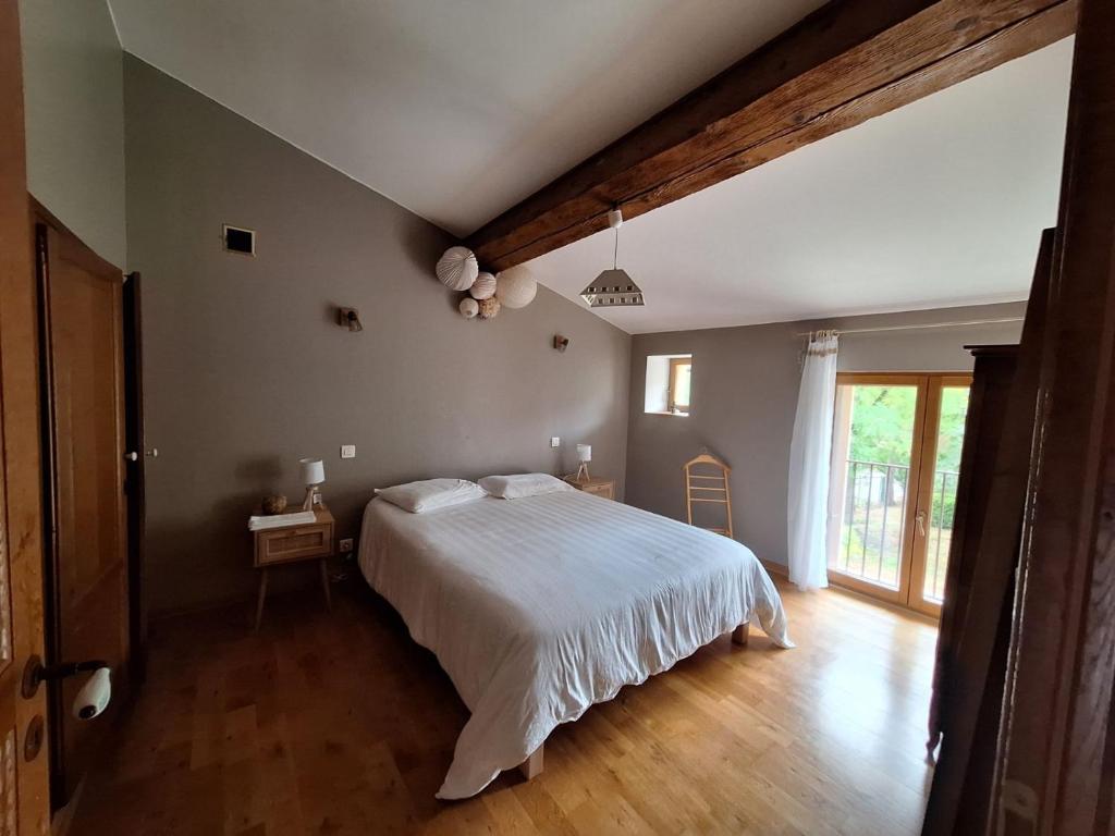 une chambre avec un lit blanc et un parquet dans l'établissement Les jardins du Canal, à Sainte-Eulalie