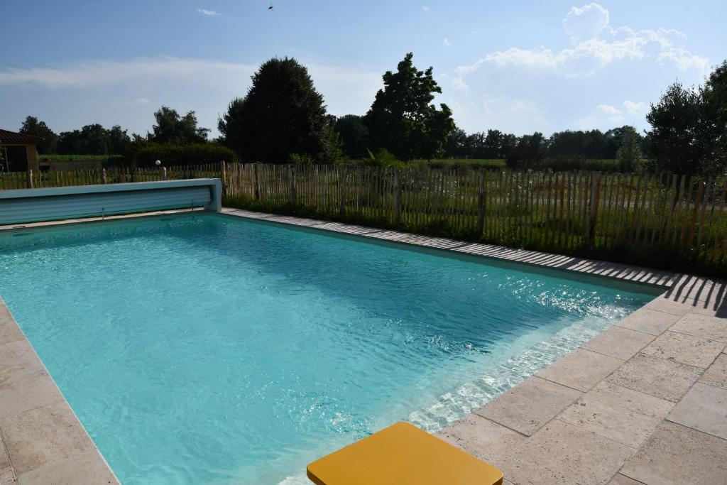 une piscine avec une chaise jaune à côté d'une clôture dans l'établissement Chambre d'hôte L'Oiseau Blanc, à Saint-Nizier-le-Désert