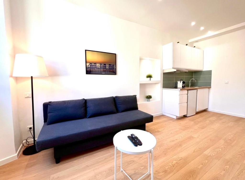 een woonkamer met een blauwe bank en een tafel bij Collet Résidence in Nice