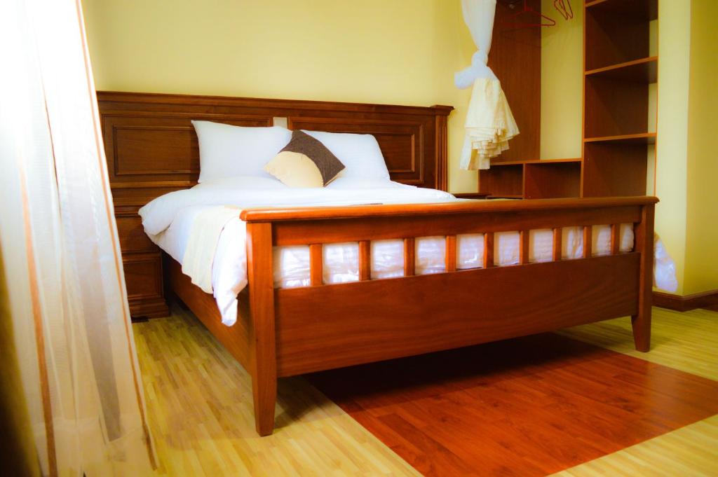 a bedroom with a wooden bed with white sheets and pillows at Red Ruby Hotel in Nairobi