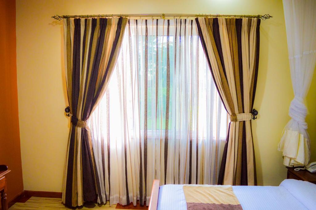 a bedroom with a large window with curtains at Red Ruby Hotel in Nairobi