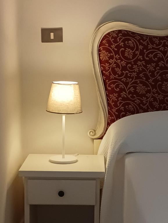 a lamp on a nightstand next to a bed at Hotel Corallo in Castiglioncello