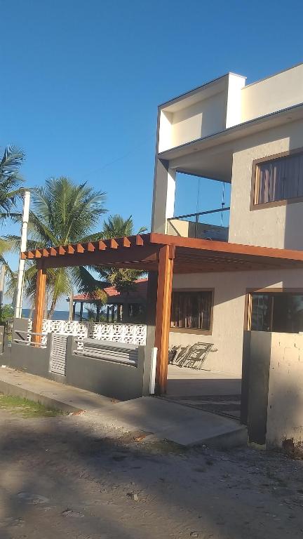 a building with a wooden pergola in front of it at Casa de Praia, pé na areia Guaratiba Prado - Bahia in Prado