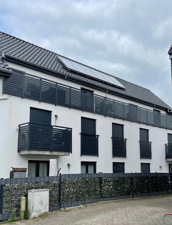 a white building with black windows and a fence at Ferienwohnung Licina in Lauenburg