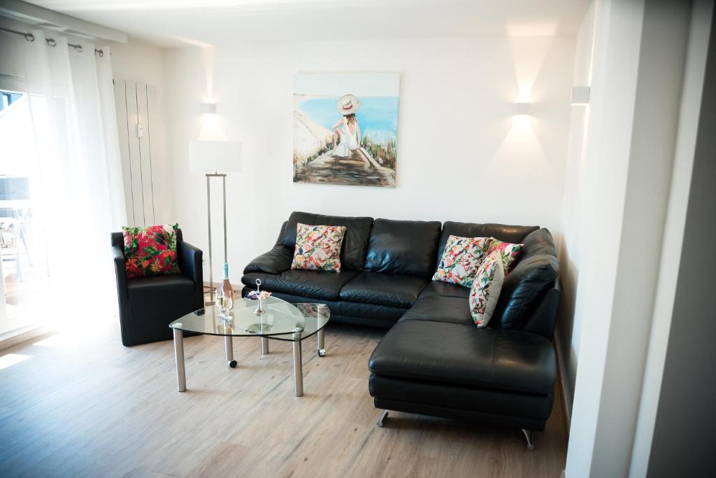 a living room with a black leather couch and a glass table at Terrassenwohnung mit Gartenblick in Solingen