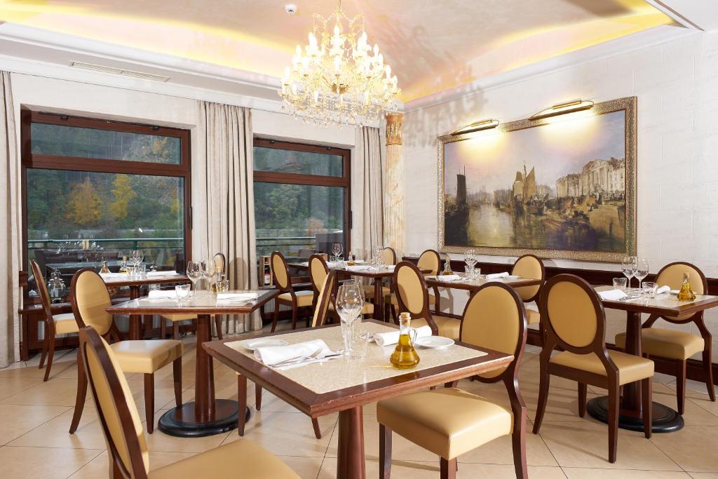 a restaurant with tables and chairs and a chandelier at Retro Riverside Wellness Resort in Karlovy Vary