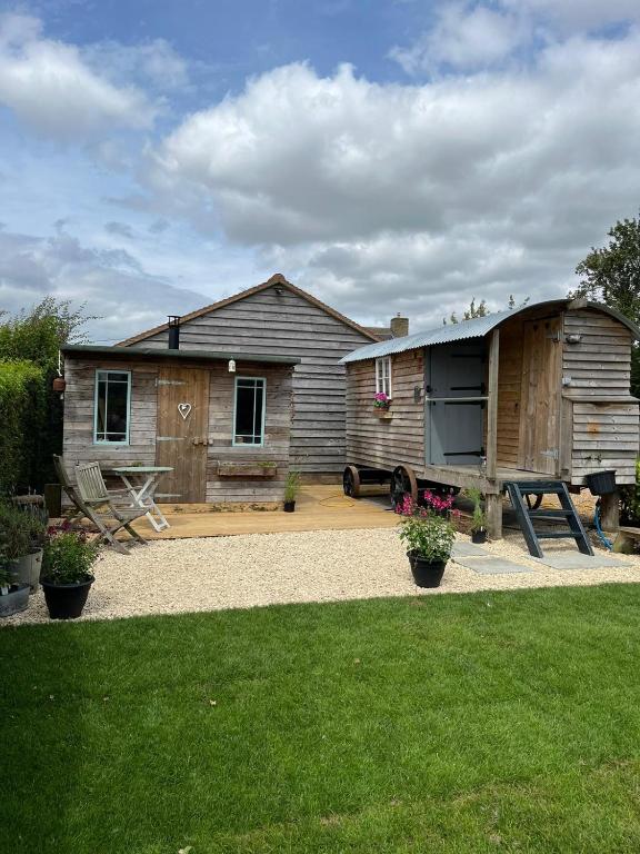 a house with a trailer and a picnic table at The Hen House Shepherds hut with hot tub in Chittoe