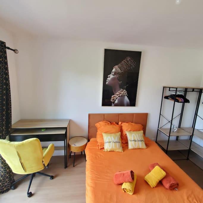 Cette chambre comprend un lit avec des draps orange et un bureau. dans l'établissement Prospérité et Abondance à 24min de Disney et Center parcs, à Meaux