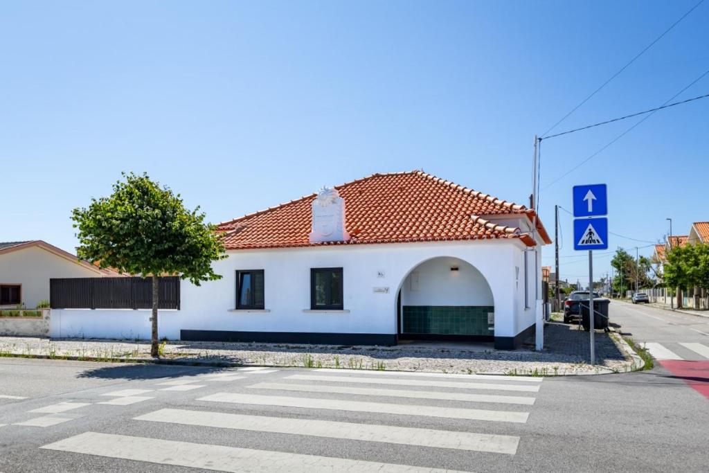 a white building with a red roof on a street at Casa das Camarinhas in Aveiro