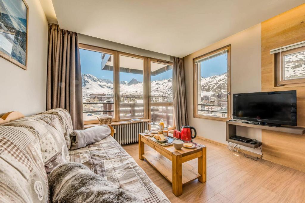 un salon avec un canapé et une télévision et des montagnes dans l'établissement Résidence Tour Du Lac - Appartement 3 entièrement rénové, vue époustouflante MAE-3431, à Tignes
