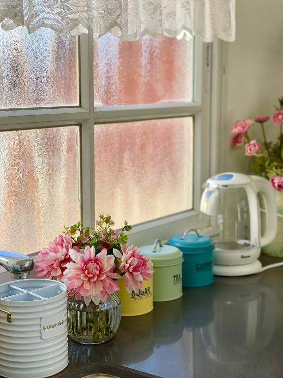 a kitchen counter with pink flowers in jars and a window at Suits יחידת נופש מתוקה באילת in Eilat