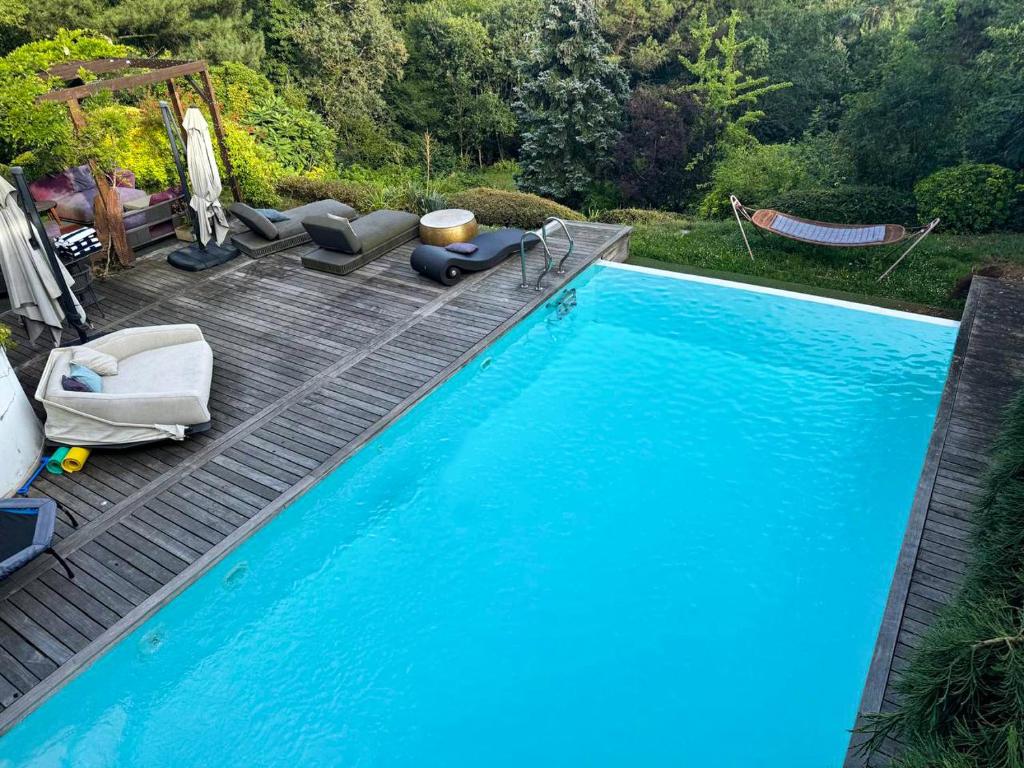 une grande piscine bleue avec des chaises et une terrasse dans l'établissement LA MAISON DE ROBINSON, au Plessis-Robinson