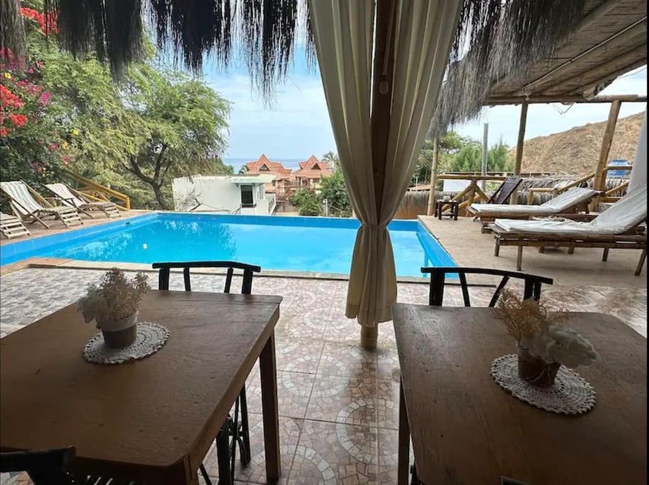 a pool with two wooden tables and chairs next to it at Nuevo Apartamento en Máncora Las Pocitas in Máncora