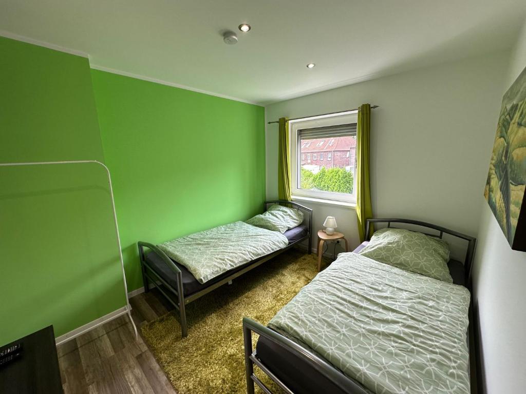 two beds in a room with green walls at Ferienhaus in Duisburg für bis zu 9 Personen - Arbeiten im Ruhrgebiet in Duisburg
