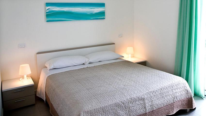 ein Schlafzimmer mit einem Bett mit zwei Lampen und einem Gemälde in der Unterkunft Residence Blumare in Martinsicuro