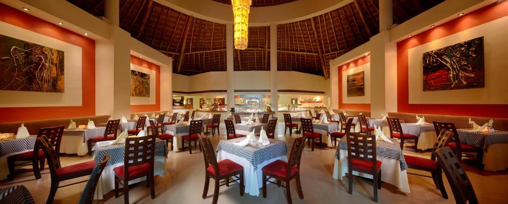 a restaurant with tables and chairs and a chandelier at Desire Riviera Maya Resort All Inclusive - Couples Only in Puerto Morelos