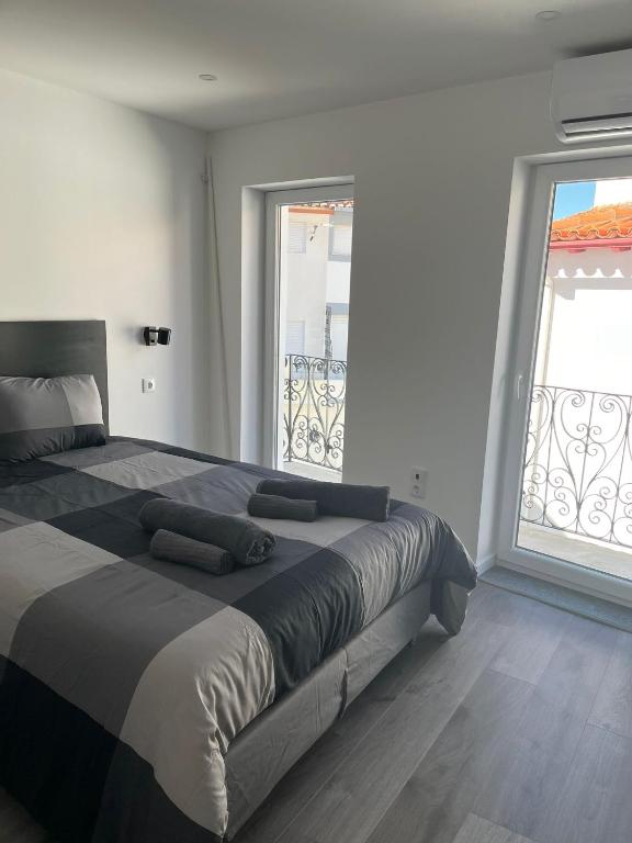 a bedroom with a large bed with two large windows at H I Alojamento in Manteigas