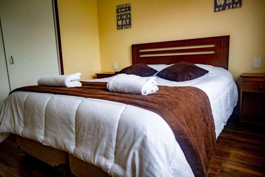 een slaapkamer met een groot bed en handdoeken bij Apartamentos Entre Fronteras in Punta Arenas