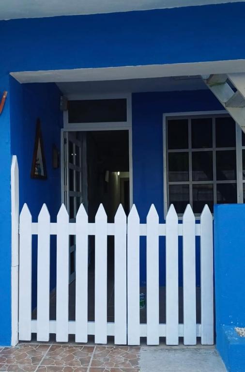a white picket fence in front of a blue house at Casa Azul in Isla Mujeres