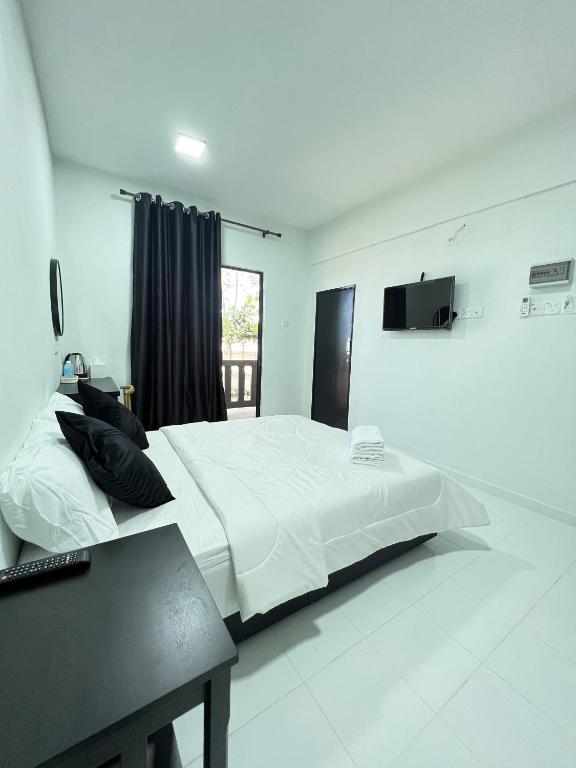 a bedroom with a large white bed and a television at Barokah Resort in Bachok