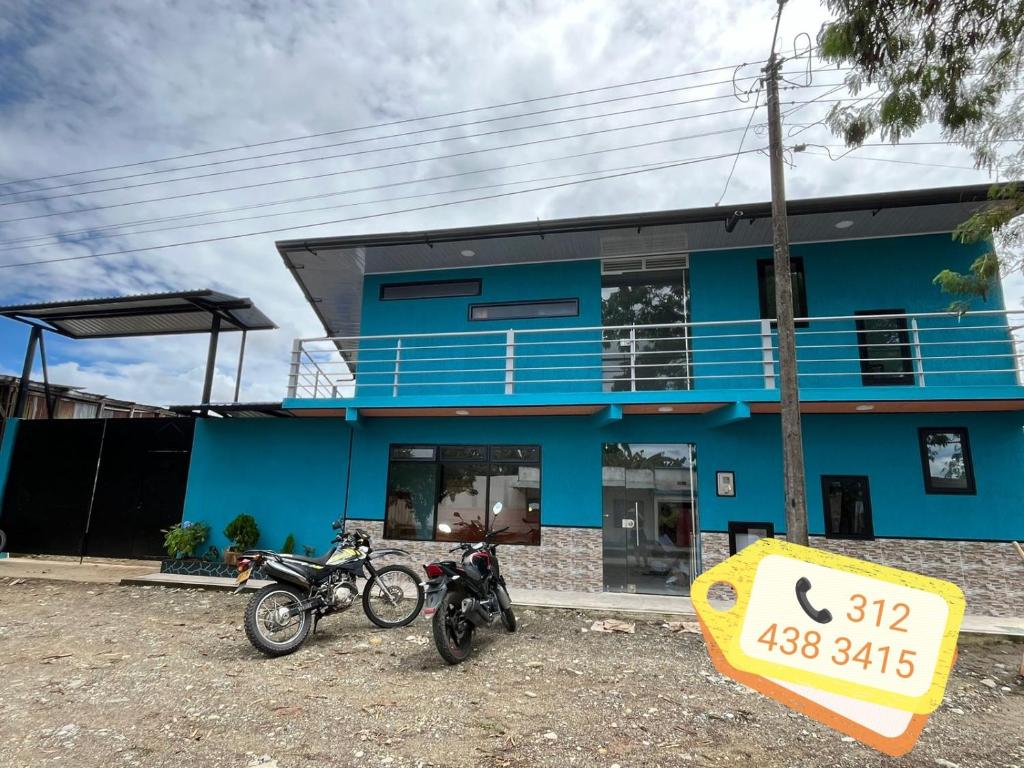 two motorcycles parked in front of a blue building at Hotel los pinos in Mesetas