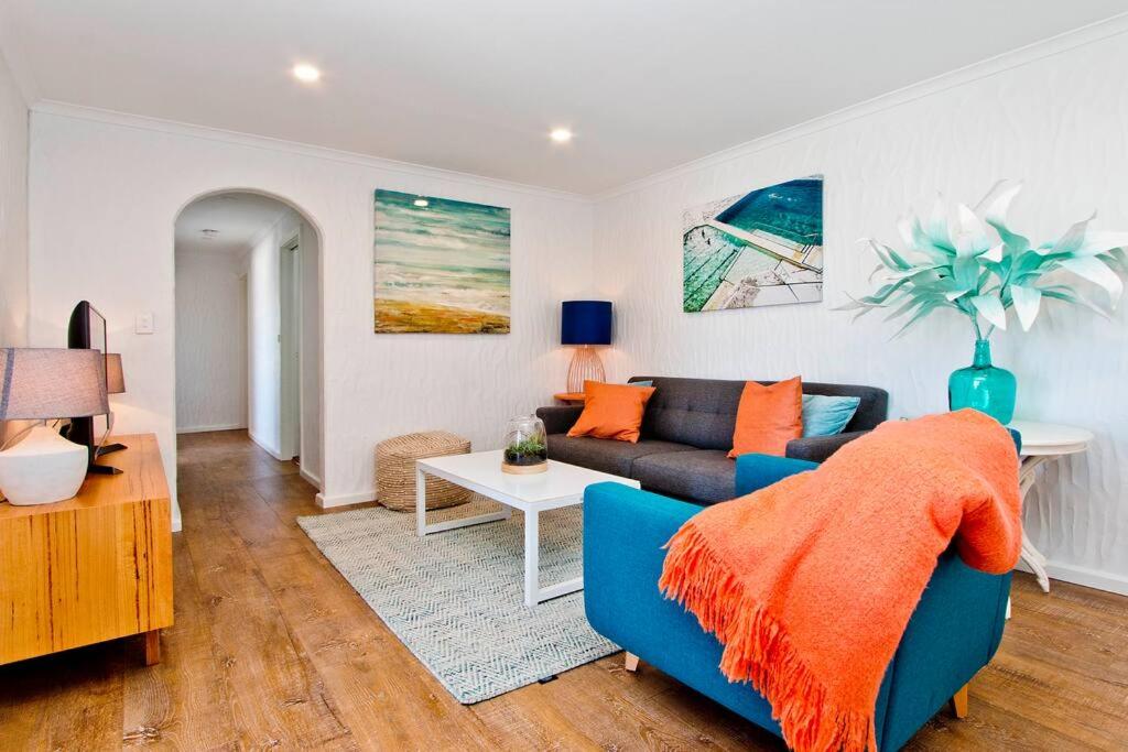グレネルグにあるGetaway on Gordon - Comfortable stylish apartmentの青いソファとテーブルのあるリビングルーム
