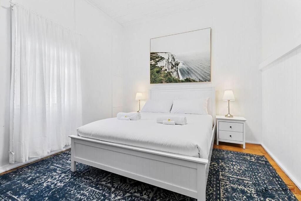 Un dormitorio blanco con una cama y un cuadro en la pared. en Sandown Beachside Cottage, en Bongaree